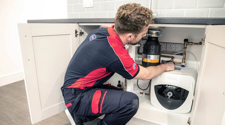 Plumber carrying out repair under the sink