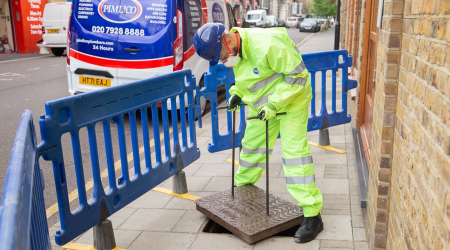 A pimlico engineer accesses an outside drain to inspect the water lines