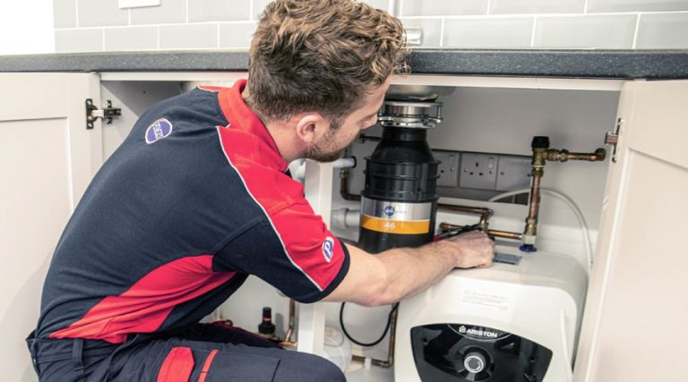 A Pimlico engineer investigates a plumbing issue under a sink