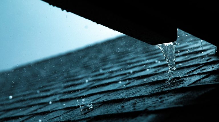 Water cascades down onto the roof below from a blocked gutter