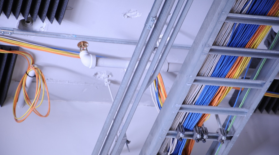 A photo of a commercially wired ceiling, complete with fire detector alarm and sprinkler system