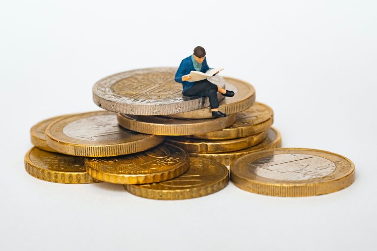 male figurine sat atop multiple coins contemplating on how to save money