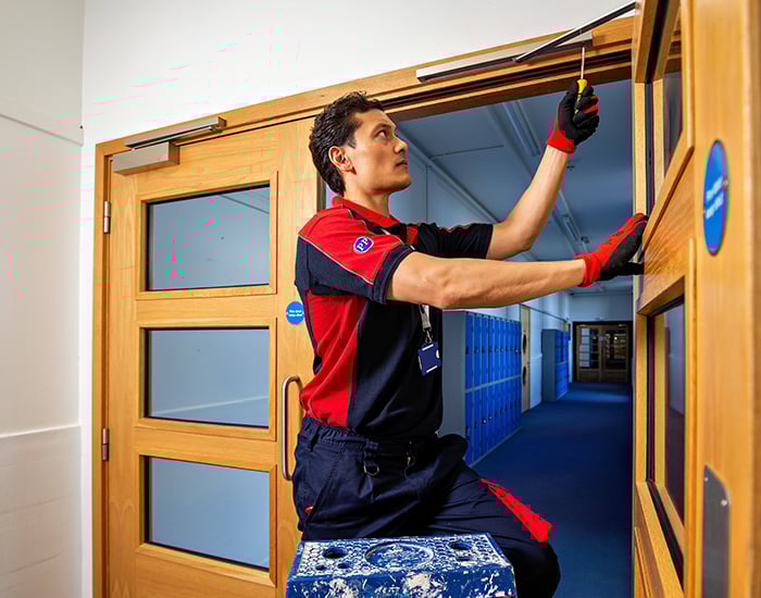 Pimlico carpenter fixing a fire door in a school