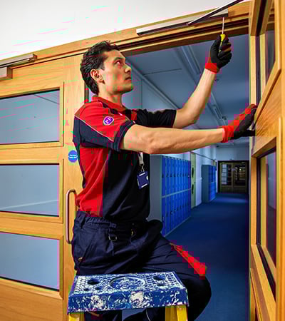 Pimlico carpenter fixing a fire door in a school