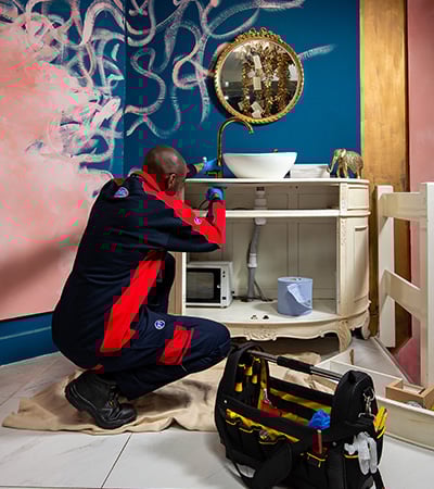 Pimlico plumber working under a sink