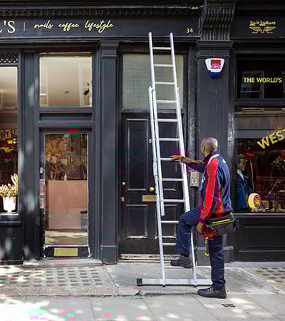 Pimlico roofer going up a ladder outside a shop