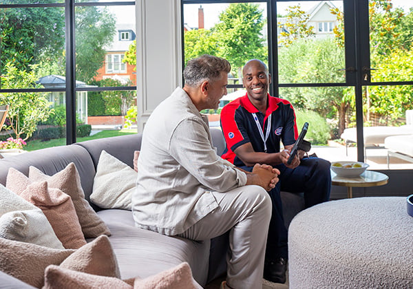 Electrician talking to customer on the sofa about 7 day pricing
