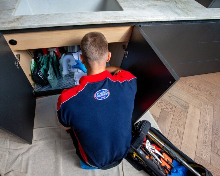 A plumber investigating underneath a kitchen sink