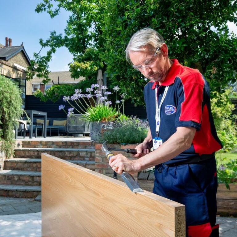 A man in the garden repairing a door